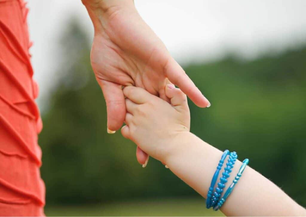 Nahaufnahme von Händen eines Kindes in den Händen eines Erwachsenen. Symbol für Energiearbeit und Unterstützung für Kinder.